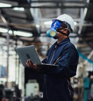 Officials from the Department of Hazardous substances control bureau is investigating the leak of a hazardous chemical in a chemical plant. Man with protective mask and computer laptops in factory